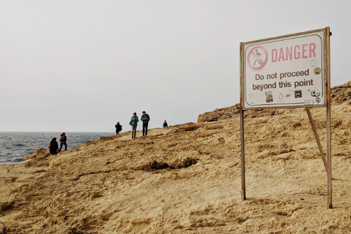 People on cliff with sign of danger
